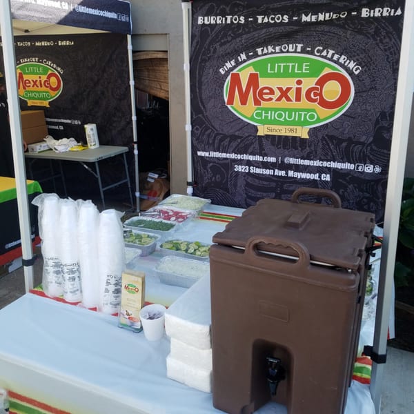 Little Mexico Chiquito catering setup with food trays, cups, and a large beverage dispenser.